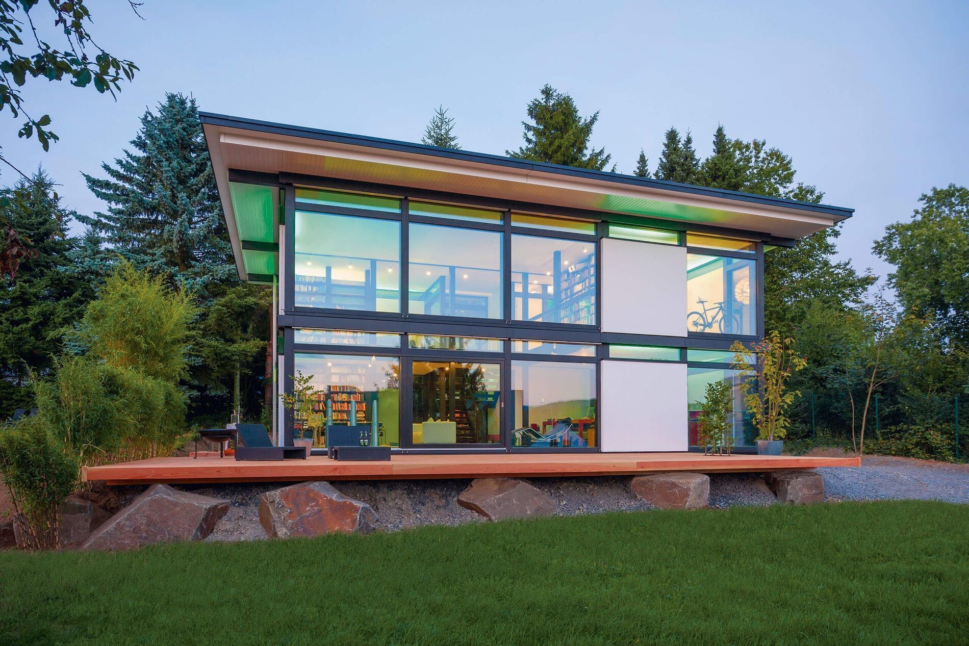 Futuristisches Fachwerkhaus mit glasierter Fassade und grünem Umfeld