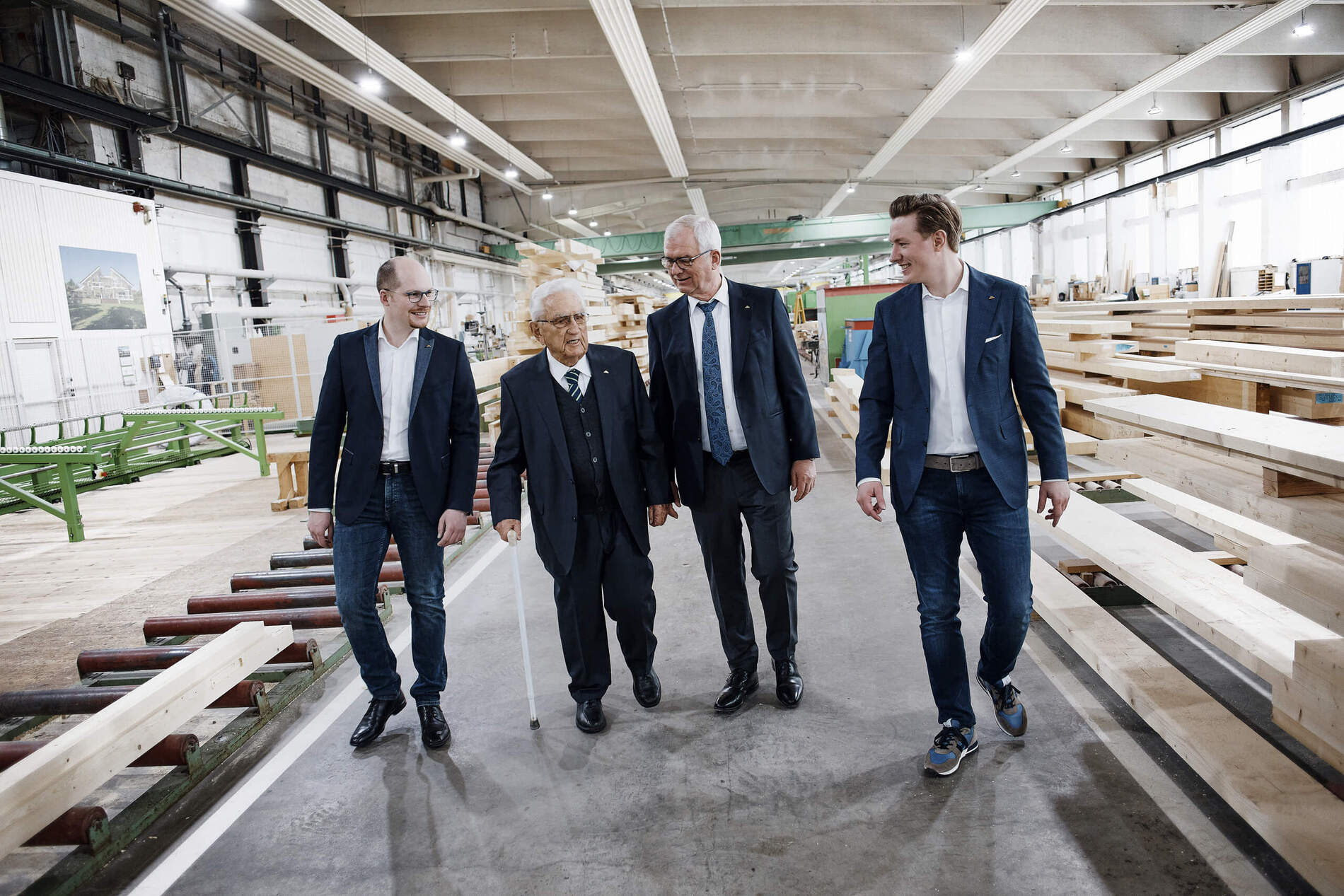 Besuch in einer Holzverarbeitungshalle Vier Männer gehen durch eine Holzverarbeitungshalle