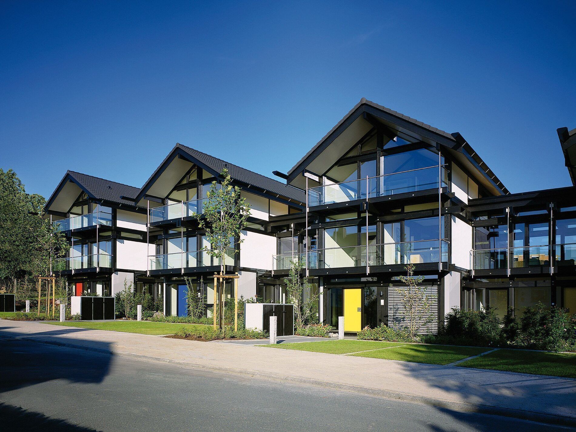 Moderne Wohngebäude mit Glasfassade und Gärten Ansicht von mehreren modernen Häusern mit schrägen Dächern und Fenstern