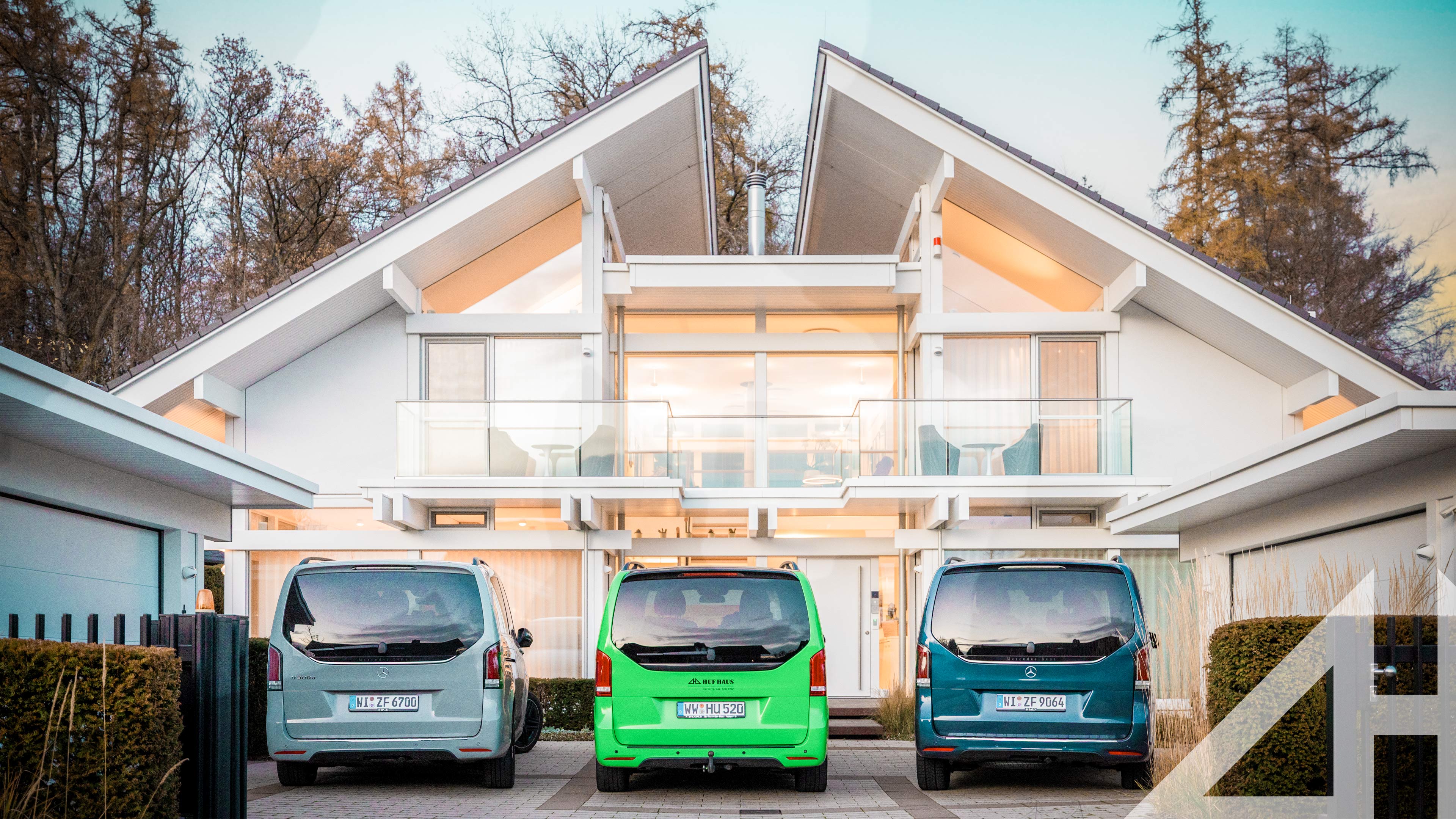 Futuristisches Haus mit großen Fenstern und drei Autos davor