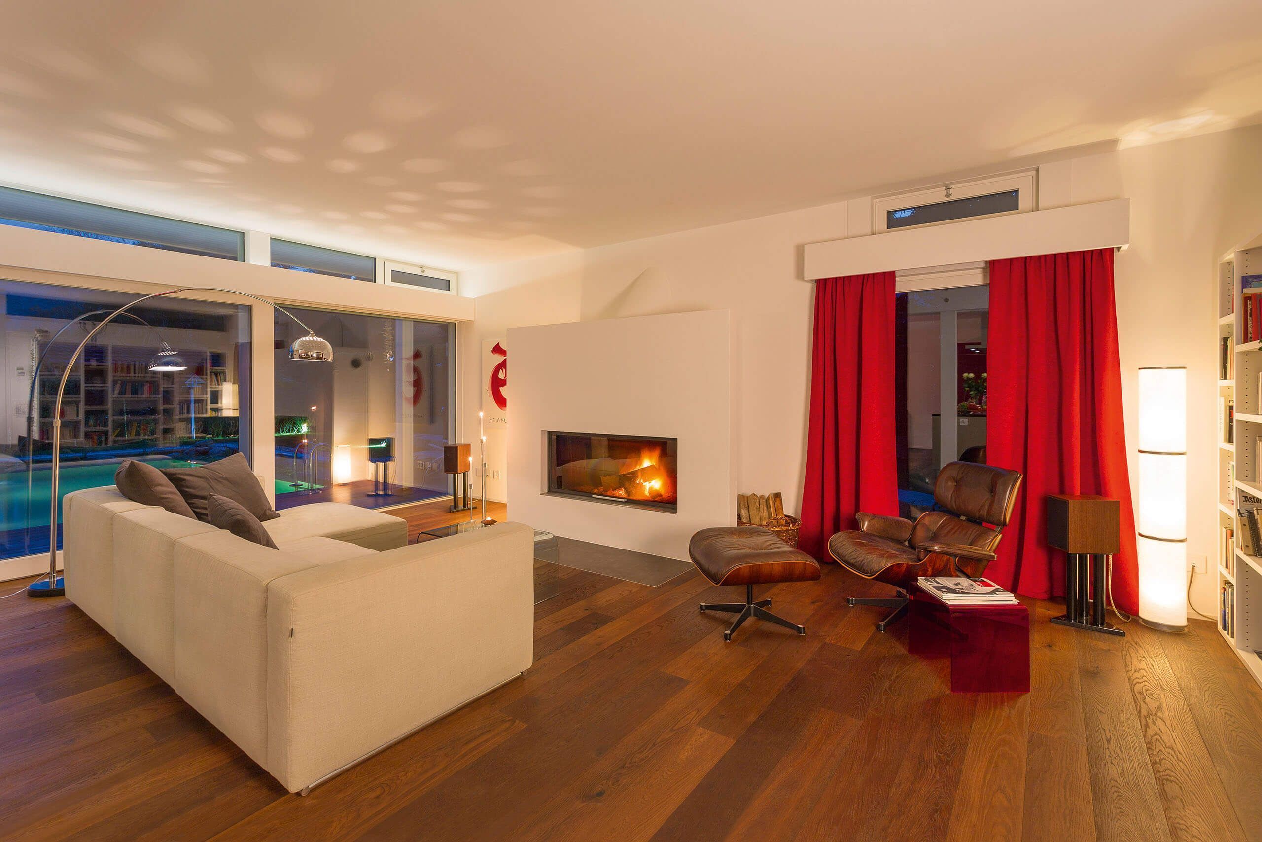 Modernes Wohnzimmer mit Kamin und roter Gardine Gemütliches Wohnzimmer mit eleganter Einrichtung und Fensterblick