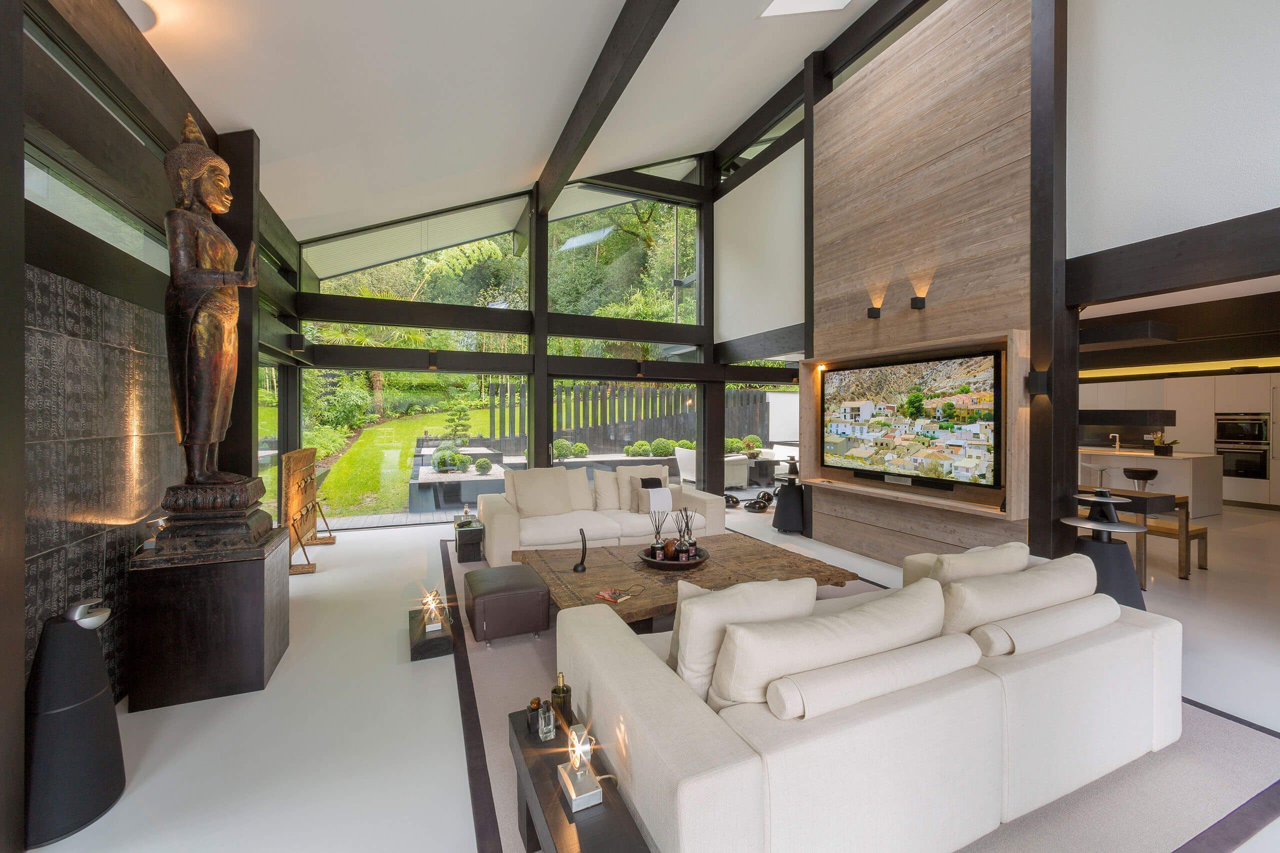 Moderne Wohnzimmereinrichtung mit Gartenblick Elegantes Wohnzimmer mit Skulptur, moderner Einrichtung und großem Fernseher