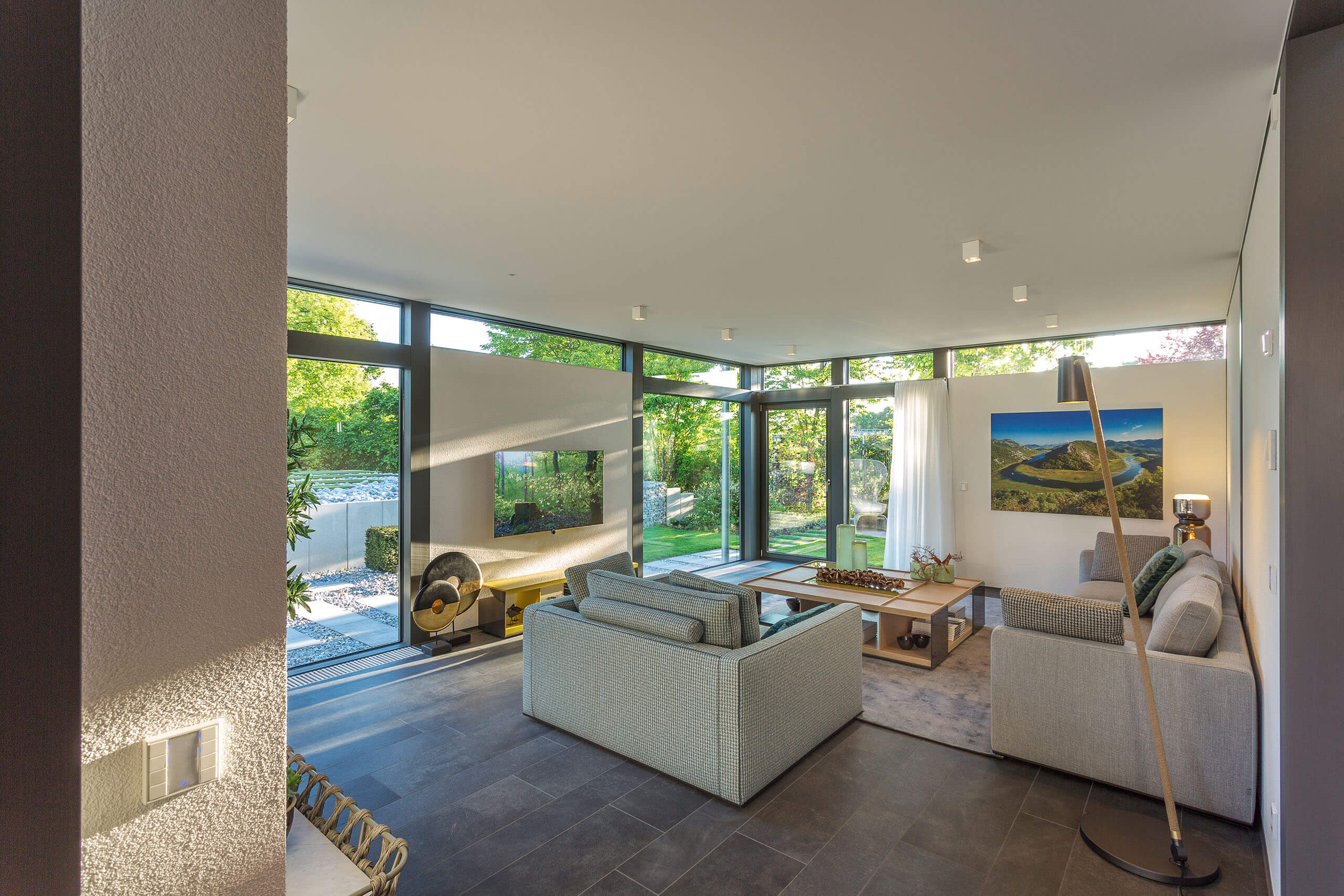 Moderne Wohnlandschaft mit großen Fenstern und Aussicht Helles Wohnzimmer mit modernen Möbeln, Blick ins Grüne