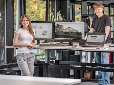 Junge Menschen in modernem Büro mit Computern Zwei Personen in einem kreativen Büro mit technischen Geräten und Zeichnungen