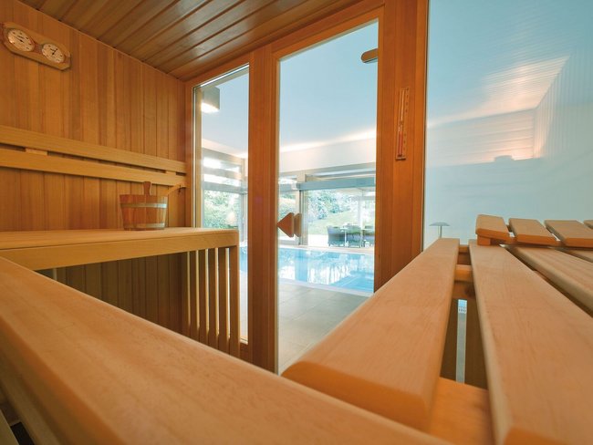 Moderne Sauna mit Poolblick in elegantem Design Innenansicht einer Sauna mit Holzelementen und Sicht auf den Pool