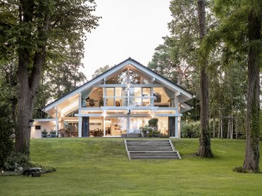 Modernes Architektenhaus am Wasser mit großzügigen Fenstern und Garten