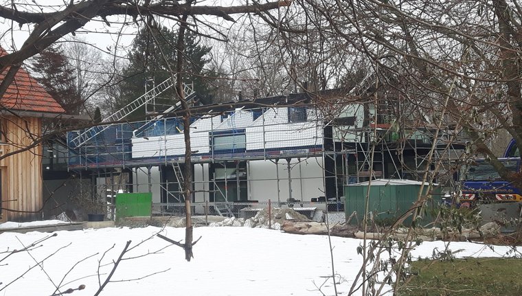 Blick auf ein Gebäude im Bau, umgeben von schneebedecktem Boden und Bäumen