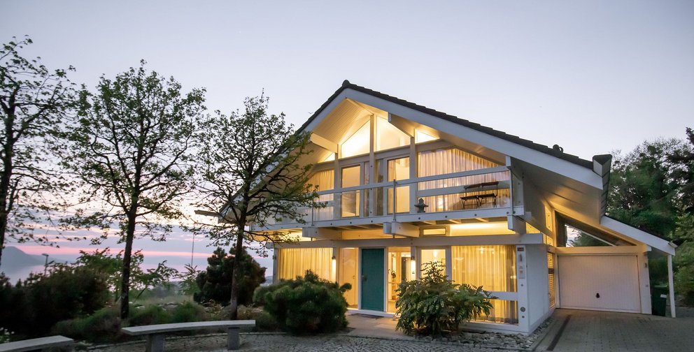 Ein modernes Haus umgeben von Bäumen bei Sonnenuntergang