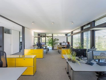 Innenansicht eines Architektenbüros mit gelben Arbeitsplätzen