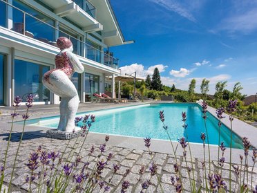 Modernes Designhaus mit Pool, Garten und Skulptur im Vordergrund