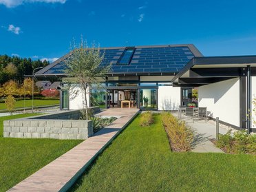 Hausansicht mit Garten und Solarmodulen auf dem Dach