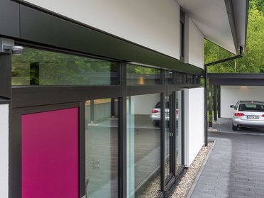 Moderne Fassade eines Familienhauses mit pinker Tür und Fenster