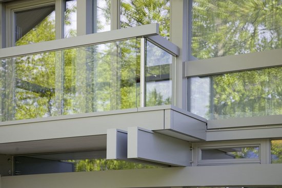 Detailaufnahme einer modernen Fassade mit Glas und Pflanzenreflexionen