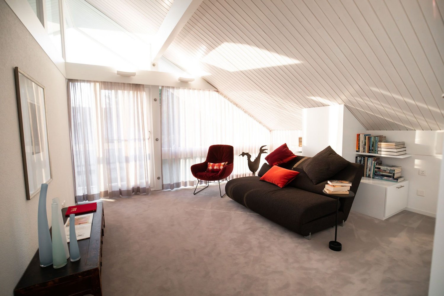 Helles, stilvolles Wohnzimmer mit Sofa, Sesseln und Bücherregal