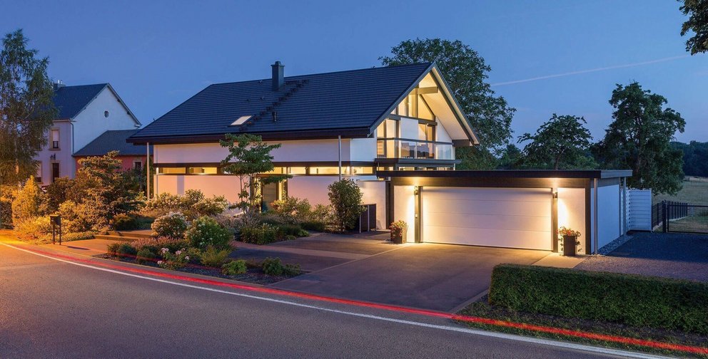 Ein modernes Haus mit Garten und Garage bei Nachtbeleuchtung