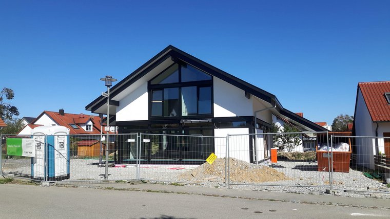 Neues Wohnhaus unter Bau in einem Wohngebiet, umgeben von Zäunen
