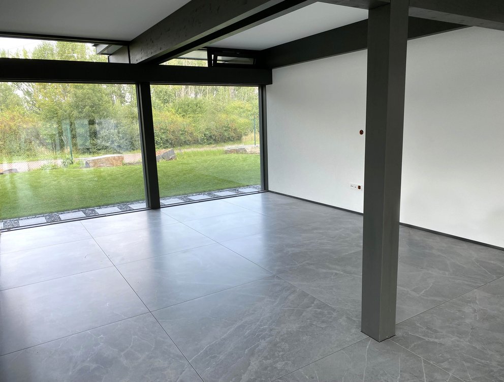 Geräumiger, leerer Raum mit Sicht auf den Garten und Betonboden