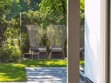 Zwei stilvolle Gartenstühle vor einem gepflegten Garten