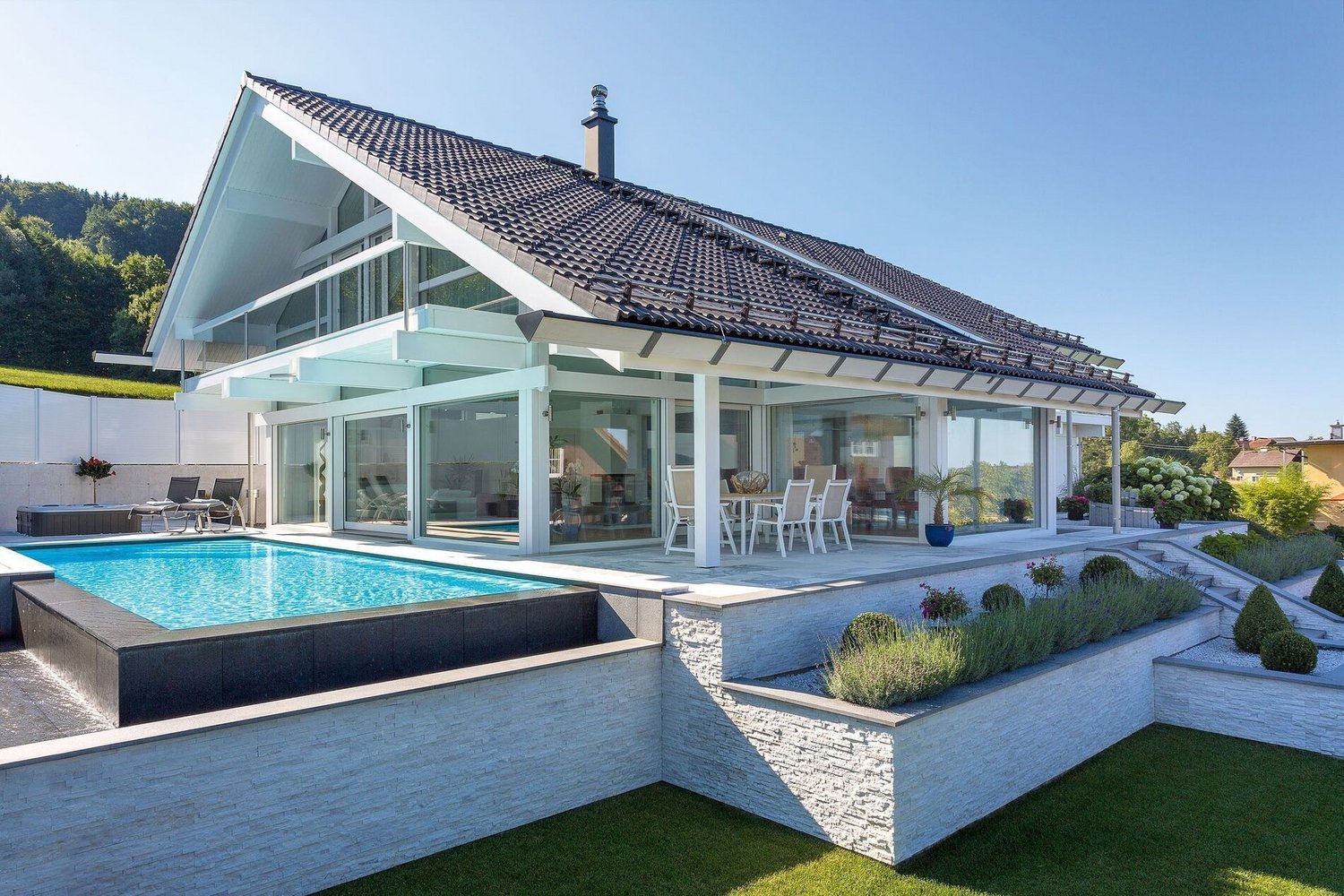 Transparente Architektur mit Blick auf Hügel und See vom Terrassengarten