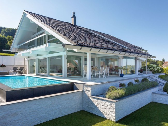 Transparente Architektur mit Blick auf Hügel und See vom Terrassengarten