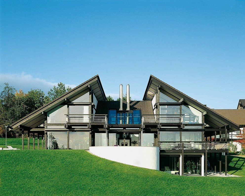 Moderne Architektur eines Hauses mit großen Fenstern Ein modernes Haus mit einer grünen Wiese und Bergblick im Hintergrund
