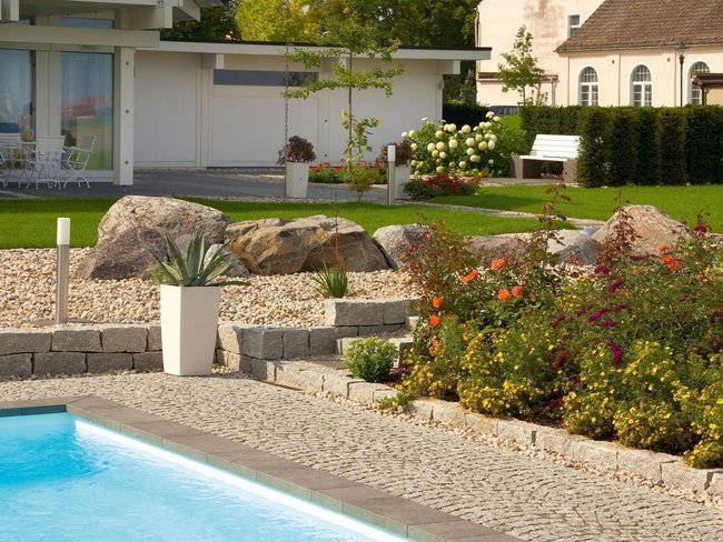 Fachwerkhaus HUF HAUS ART 4 mit Poollandschaft Moderne Architektur mit Natursteinen und Gartenblumen