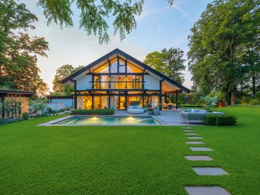 HUF Haus mit großer Glasfassade und grüner Gartenlandschaft
