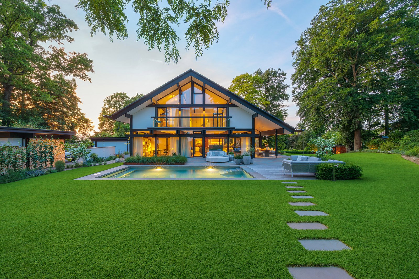 HUF Haus mit großer Glasfassade und grüner Gartenlandschaft