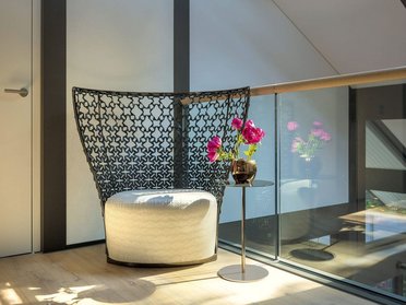 Lichtdurchfluteter Raum mit eleganter Sitzgelegenheit und Blumen