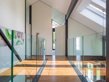 Innenansicht eines modernen Familienhauses mit Glasgeländer und viel Licht
