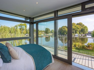 Moderne Schlafzimmeransicht mit großen Fenstern und Wasserblick