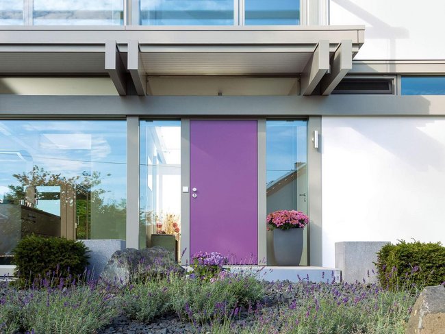 Fachwerkhaus mit lila Tür und Gartenpflanzen im Vordergrund