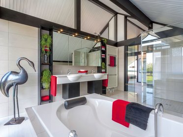 HUF Musterhaus Koblenz ebenholz 11 Helles Badezimmer mit Wanne, Spiegeln und stilvollen Dekorationen