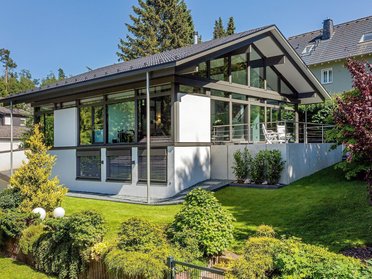 Architektenhaus umgeben von gepflegtem Garten und Bäumen