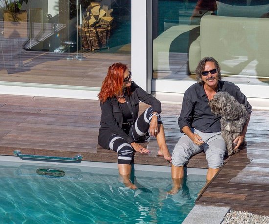 Paar mit Hund am Pool, umgeben von moderner Architektur und Garten