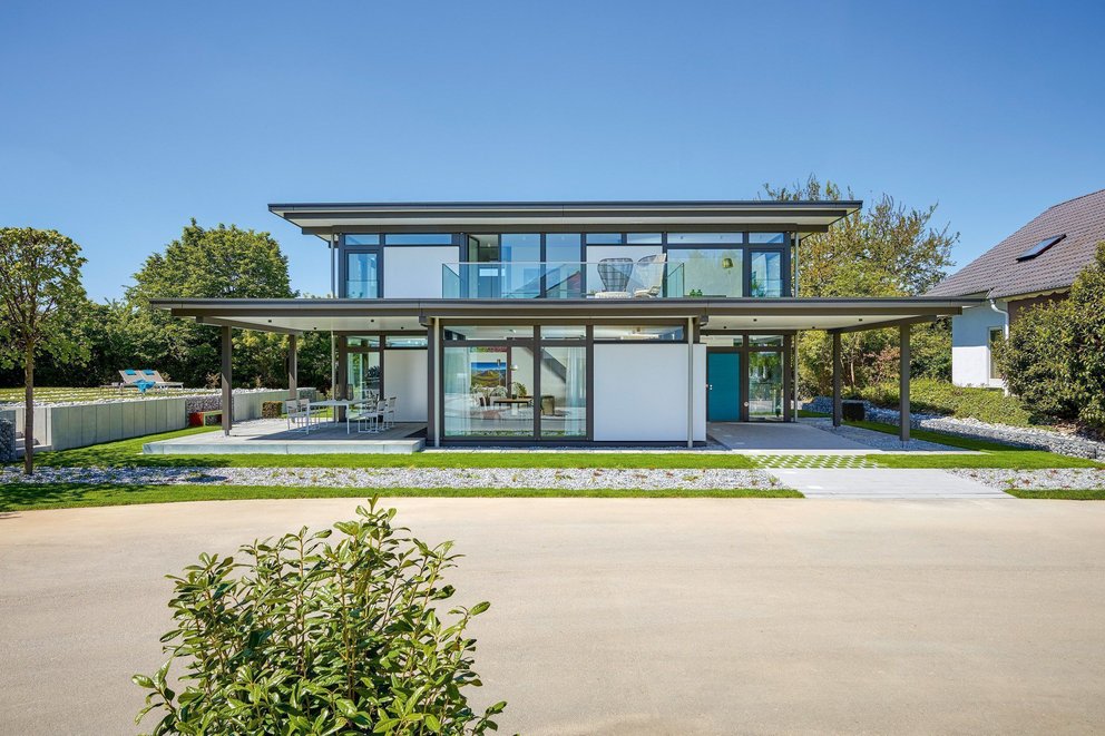 Elegantes, helles Haus mit Glasfassade und Gartenlandschaft