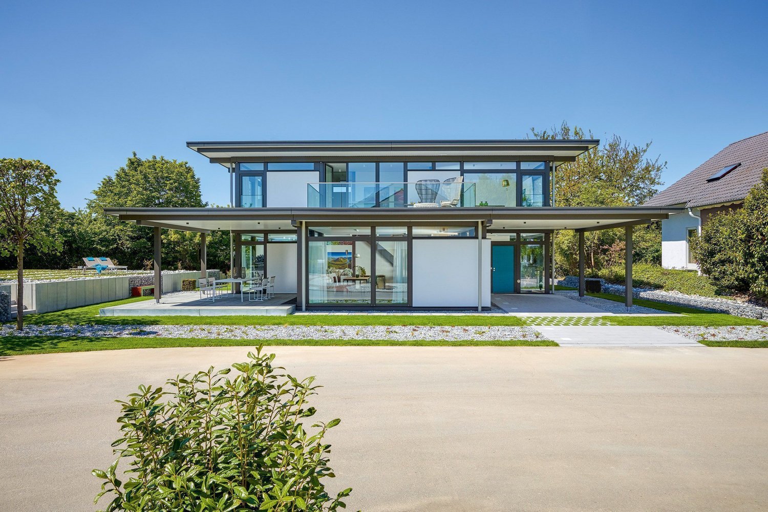 Elegantes, helles Haus mit Glasfassade und Gartenlandschaft