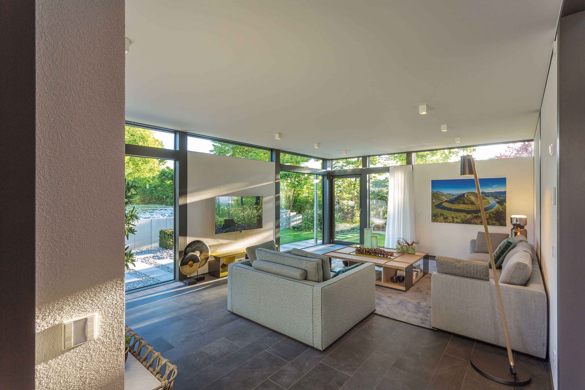 Jubiläumskalender 110 Jahre HUF HAUS Moderne Wohnlandschaft mit großen Fenstern und Blick ins Grüne