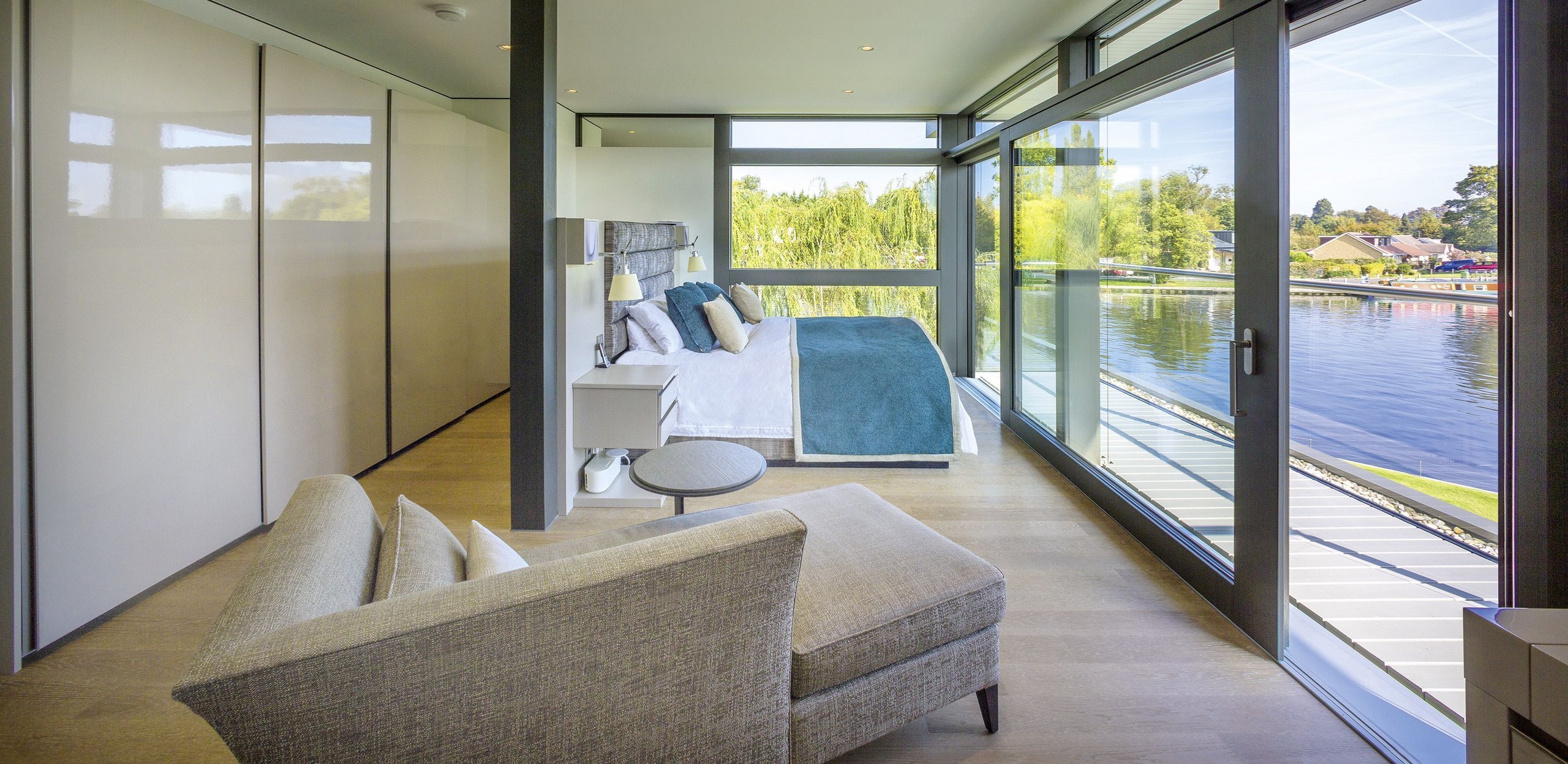 Elegantes Schlafzimmer mit großen Fenstern und Wasseraussicht