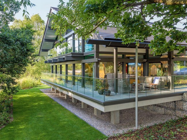 Elegantes Haus mit Glasfassade und Gartenlandschaft