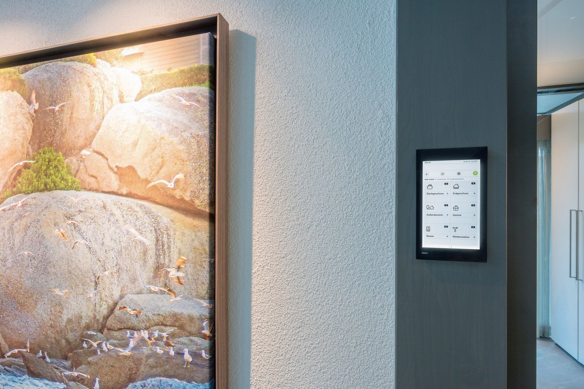 A sleek wall featuring artwork and a digital touchscreen interface