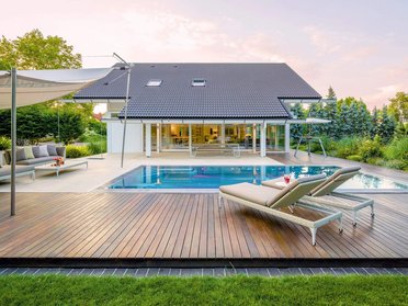 Weißes Fachwerkhaus mit Doppelpultdach, Pool und großzügiger Terrasse.