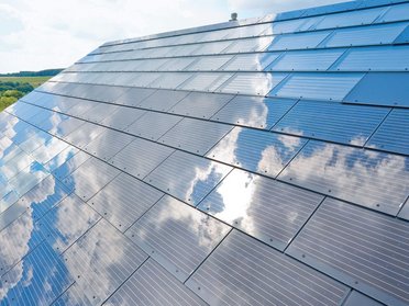 Ansicht von Solarzellen mit Wolkenreflexionen auf einem Dach