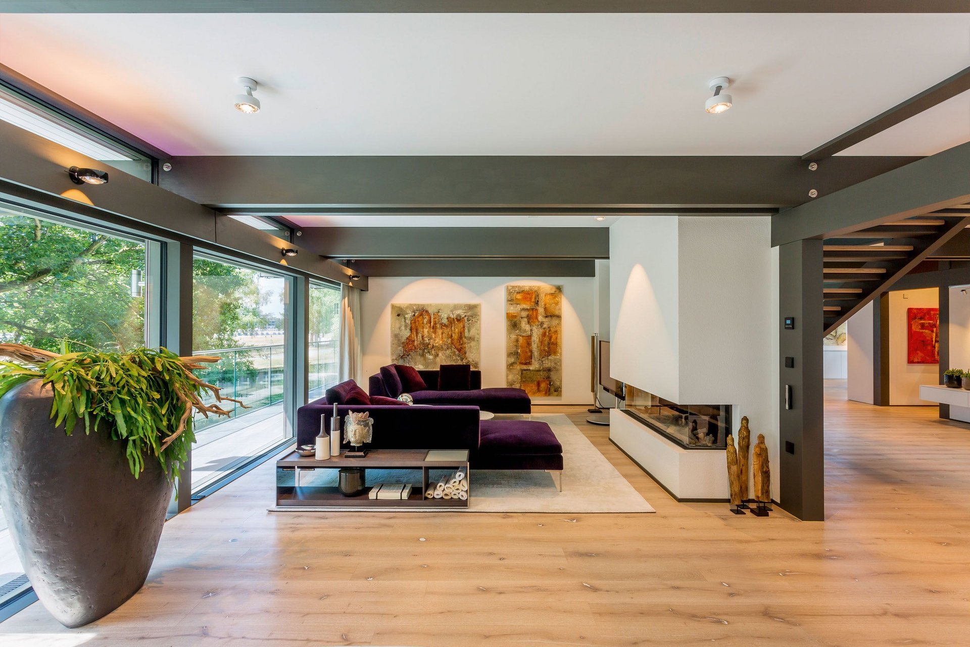 Spacious, stylish living area featuring purple couches and art pieces