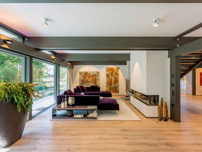 Spacious, stylish living area featuring purple couches and art pieces