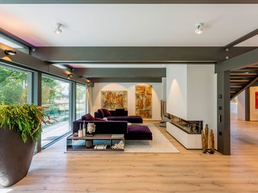 Spacious, stylish living area featuring purple couches and art pieces