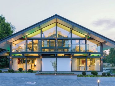 Helles modernes Gebäude mit großer Glasfront und Landschaftsgestaltung