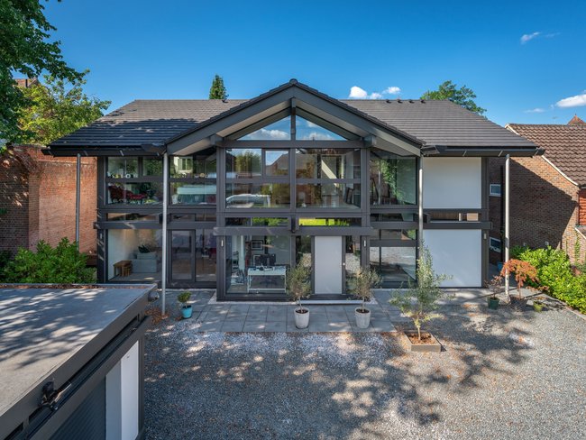 Fassade eines modernen Stadthauses mit großen Fenstern und Garten