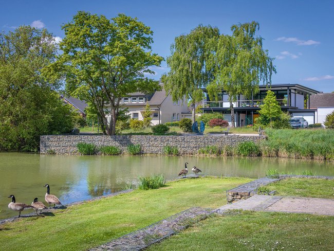 Modernes Designhaus mit Flachdach am Wasser Zeitgenössisches Designhaus in grüner Umgebung mit Wassersicht
