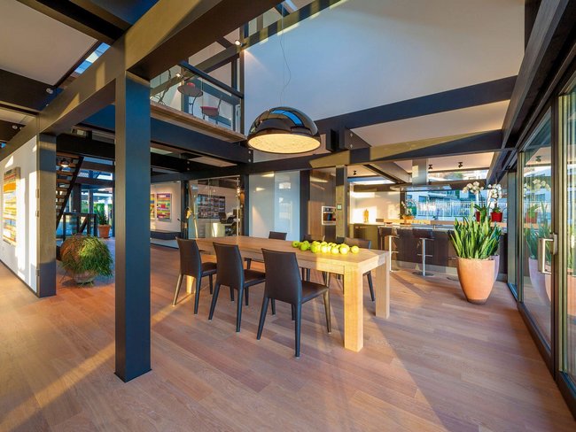 HUF Musterhaus Zuerich ART 5 ebenholz 10 Helles Esszimmer mit Holztablett, Stühlen und Küchenbereich.